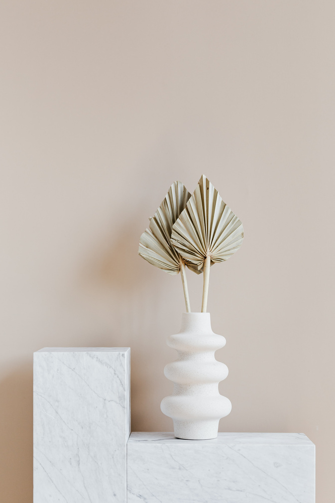 White vase with decorative leaves on shelf